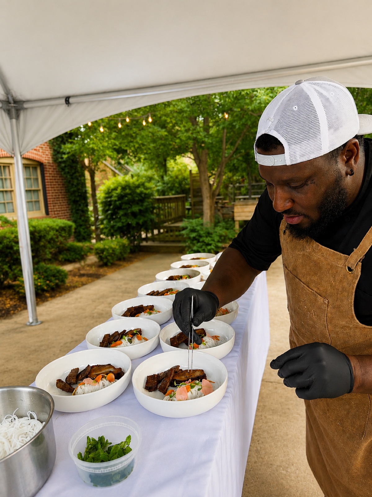 Chef Evan plating dishes under a catering tent